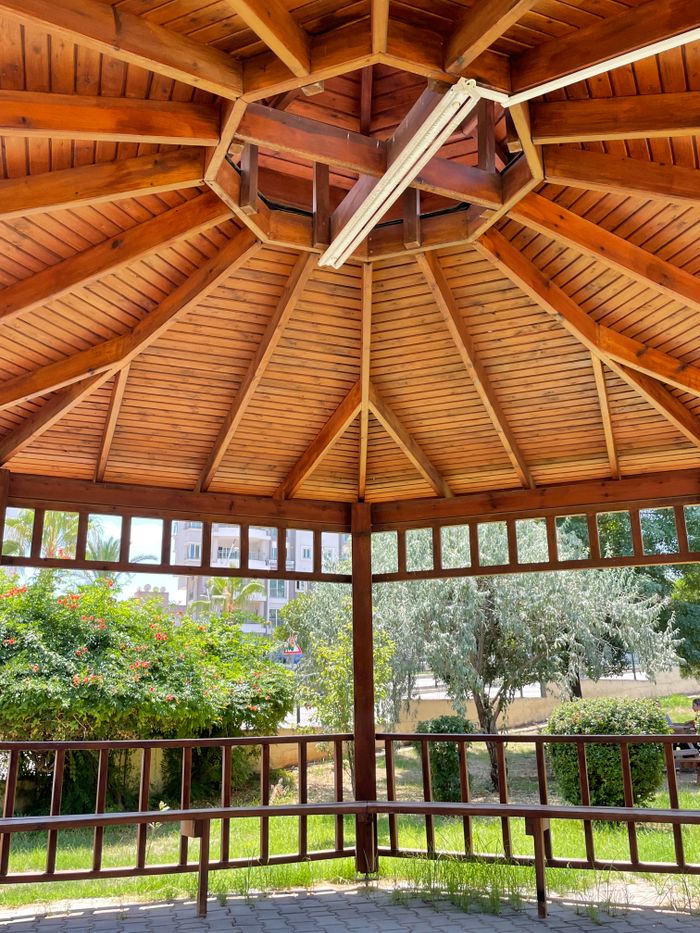 A detailed view of a wooden gazebo with lush greenery outside, perfect for relaxation.